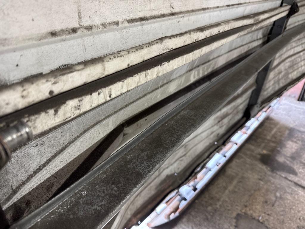  Professional garage panel repair for damaged sectional garage door with visible dents.