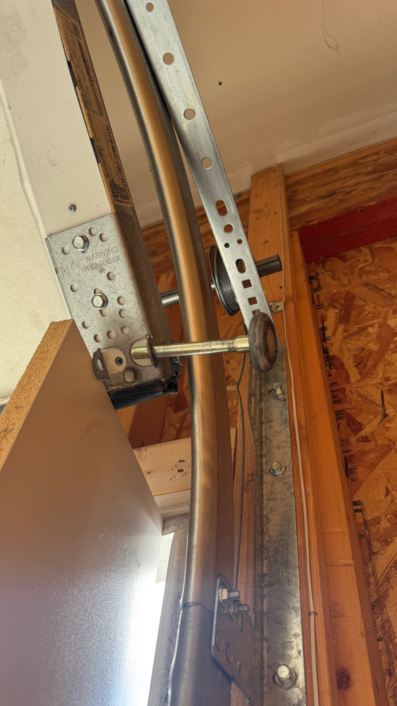  Garage door track repair showing a curved overhead track installed inside a residential garage.