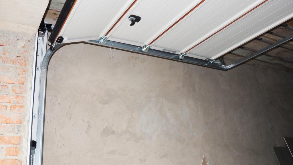 Interior view of a residential garage door showing the tracks, rollers, hinges, and sectional panels during operation